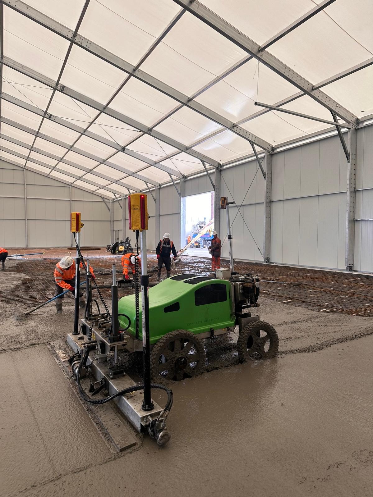 Laser screed levelling a floor inside a temporary building