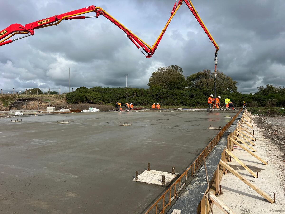 Team finishing a fresh concrete slab beside the pump